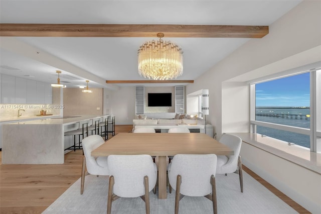 dining space featuring a chandelier, beam ceiling, light hardwood / wood-style flooring, and sink