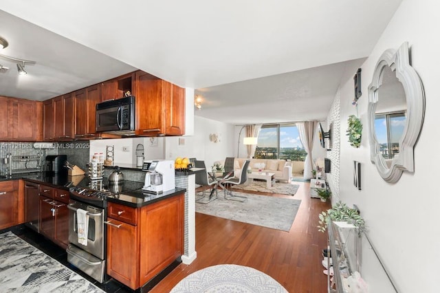 kitchen featuring sink, stainless steel range with electric cooktop, dark hardwood / wood-style flooring, dark stone counters, and backsplash