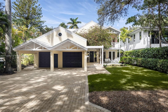 view of front of home with a garage, a balcony, and a front yard