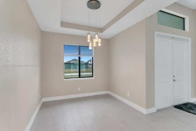 empty room with an inviting chandelier and a raised ceiling