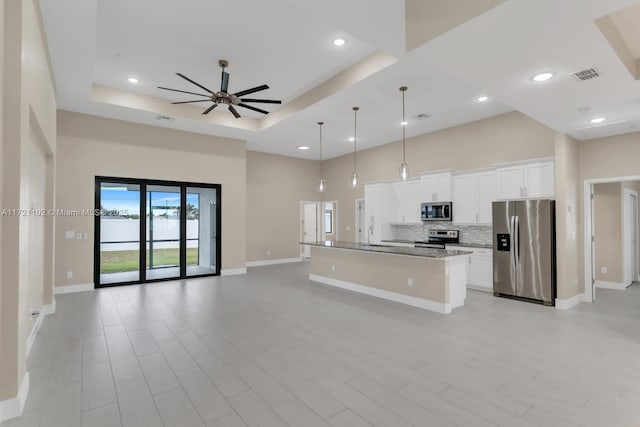 kitchen with light stone counters, pendant lighting, a kitchen island with sink, white cabinets, and appliances with stainless steel finishes