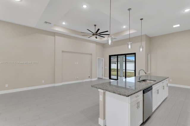 kitchen with dishwasher, light stone counters, a tray ceiling, sink, and white cabinetry