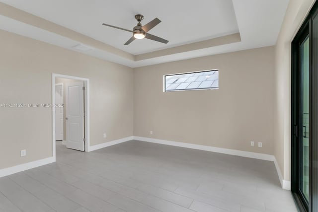 empty room featuring ceiling fan and a tray ceiling