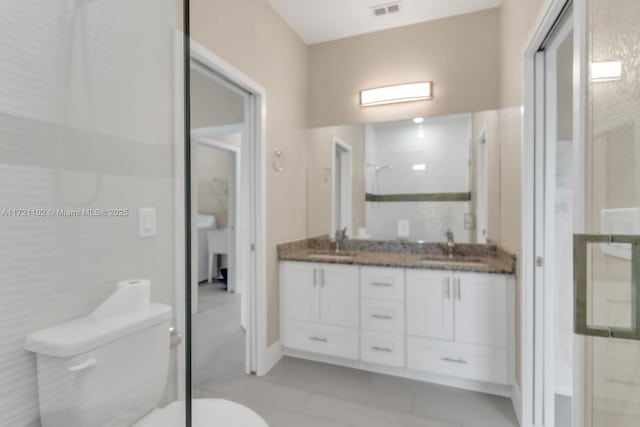 bathroom featuring toilet, vanity, tile patterned flooring, and walk in shower