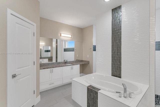 bathroom featuring vanity, tile patterned flooring, and tiled bath