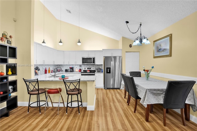 kitchen with appliances with stainless steel finishes, pendant lighting, white cabinets, and decorative backsplash