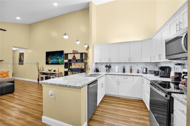 kitchen featuring sink, white cabinets, appliances with stainless steel finishes, and hanging light fixtures