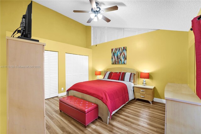 bedroom with ceiling fan, light hardwood / wood-style floors, lofted ceiling, and a textured ceiling