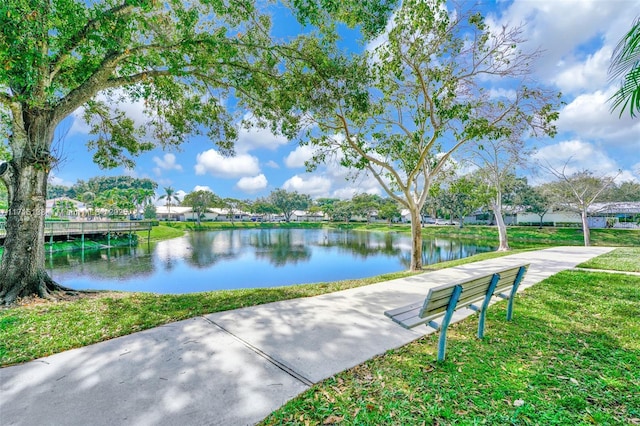 view of property's community with a water view and a lawn