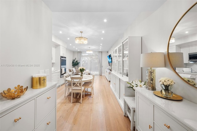 interior space with appliances with stainless steel finishes, light hardwood / wood-style flooring, white cabinetry, and hanging light fixtures