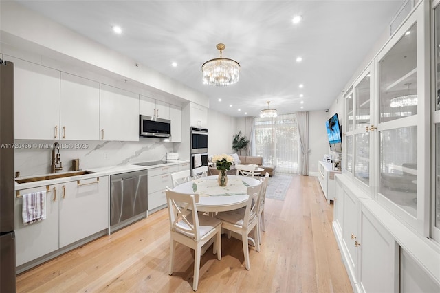 kitchen with appliances with stainless steel finishes, tasteful backsplash, sink, pendant lighting, and white cabinets