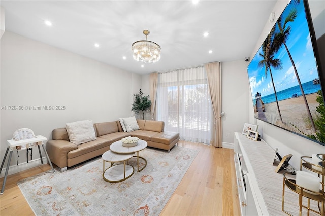 living room with light hardwood / wood-style floors and an inviting chandelier