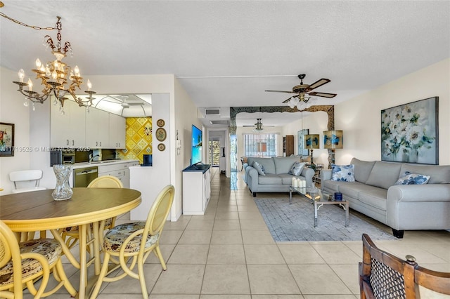 living room with light tile patterned floors, ceiling fan with notable chandelier, a textured ceiling, and sink