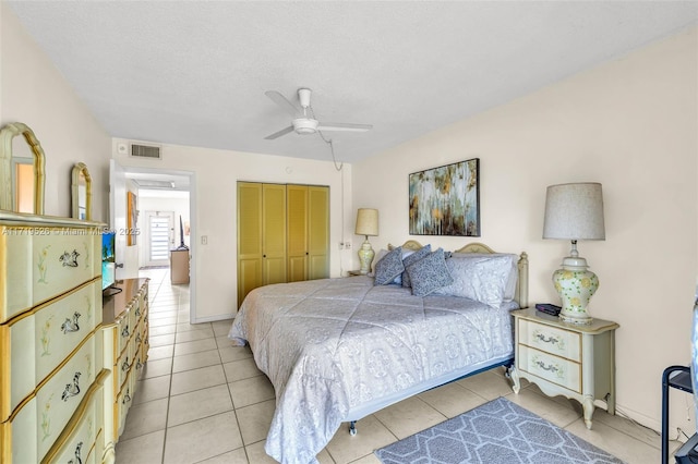 tiled bedroom with ceiling fan, a textured ceiling, and a closet