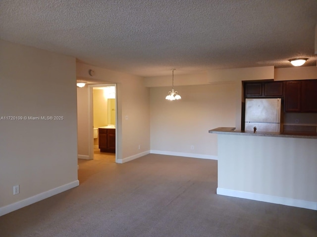 carpeted empty room with a notable chandelier and a textured ceiling