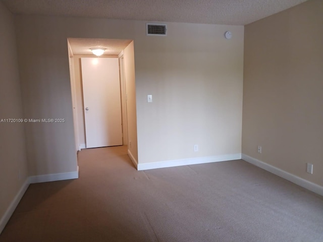 unfurnished room featuring carpet and a textured ceiling