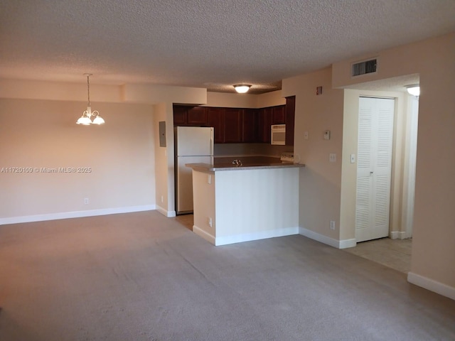 kitchen featuring hanging light fixtures, kitchen peninsula, a chandelier, white appliances, and light carpet