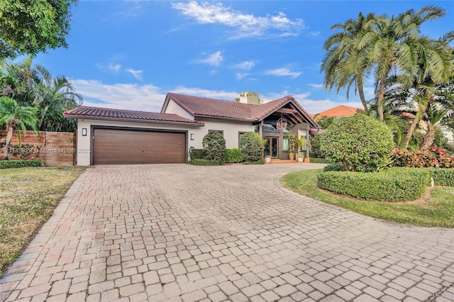 2877 NE 29th St, Fort Lauderdale, FL 33306 - view of front facade featuring stucco siding, fence, a tiled roof, decorative driveway, and a garage