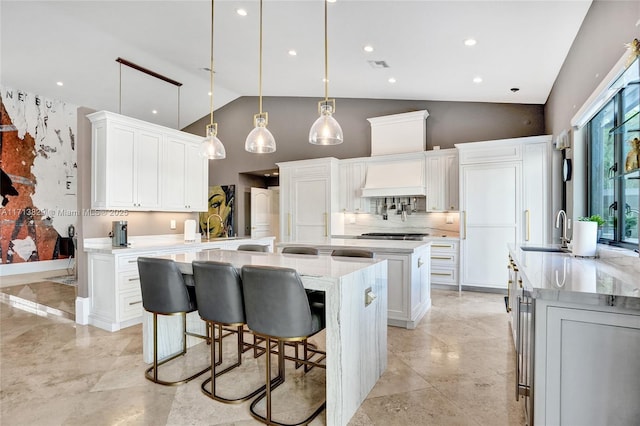 kitchen with decorative backsplash, sink, decorative light fixtures, white cabinets, and a large island