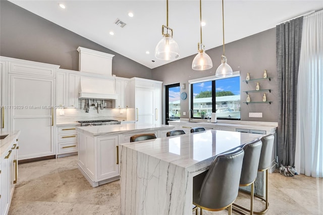 kitchen featuring custom range hood, white cabinetry, a kitchen island, and hanging light fixtures