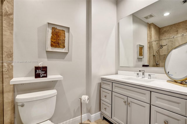 bathroom with a tile shower, vanity, and toilet