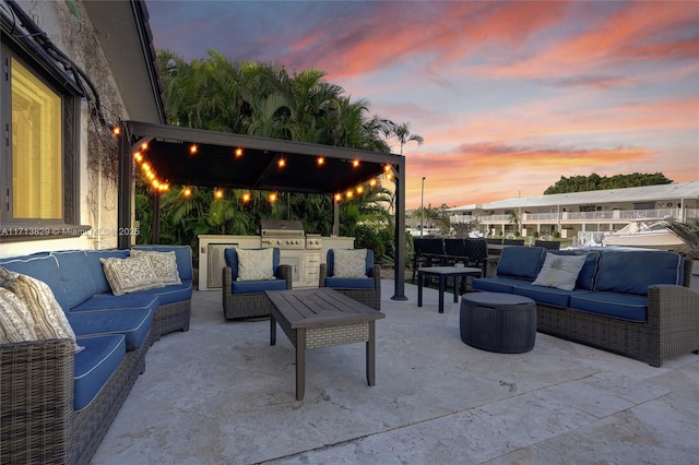 patio terrace at dusk featuring outdoor lounge area, an outdoor kitchen, and a grill