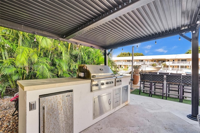 view of patio featuring an outdoor kitchen, an outdoor bar, and grilling area