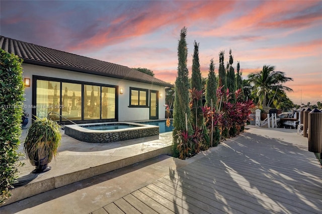 deck at dusk with an in ground hot tub