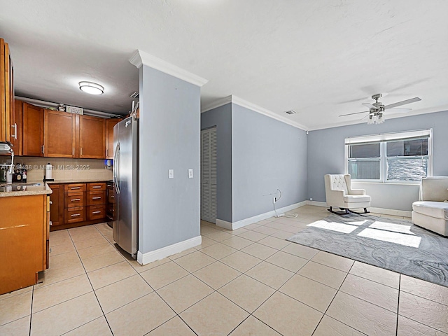 kitchen with ceiling fan, light tile patterned flooring, ornamental molding, and stainless steel refrigerator