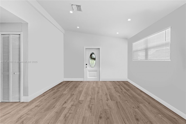 unfurnished room with lofted ceiling and light wood-type flooring