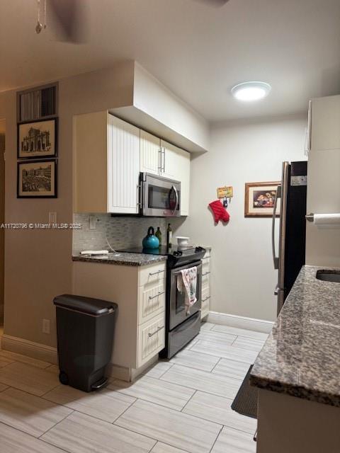 kitchen with black / electric stove, tasteful backsplash, dark stone counters, white cabinetry, and fridge