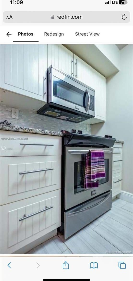 kitchen featuring stone counters, stainless steel appliances, and white cabinetry