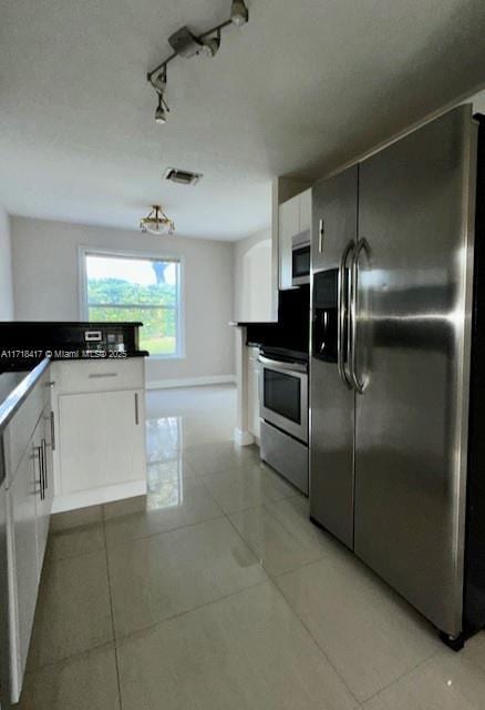 kitchen featuring light tile patterned flooring, white cabinets, stainless steel appliances, and track lighting