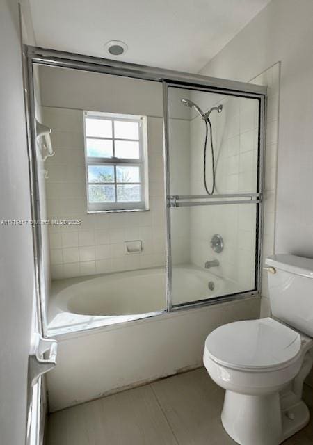 bathroom featuring shower / bath combination with glass door, tile patterned flooring, and toilet