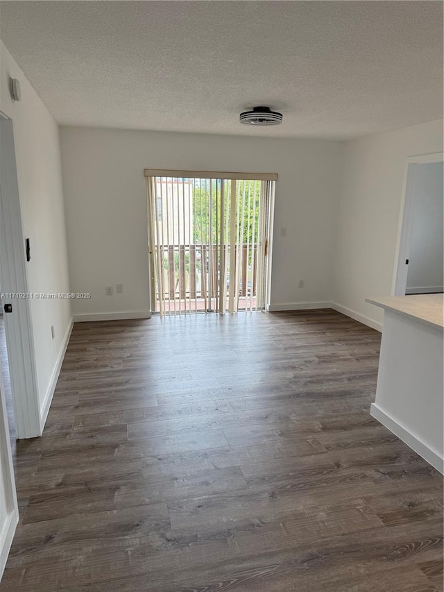 spare room with dark hardwood / wood-style floors and a textured ceiling