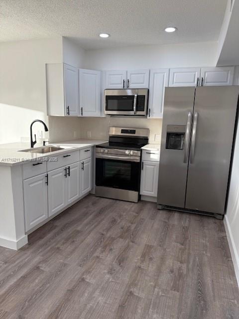 kitchen featuring sink, white cabinets, stainless steel appliances, and hardwood / wood-style flooring