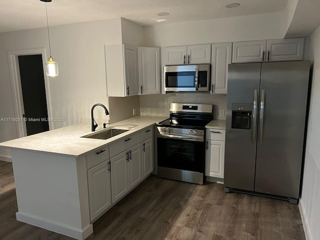 kitchen with kitchen peninsula, appliances with stainless steel finishes, sink, pendant lighting, and dark hardwood / wood-style floors