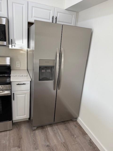 kitchen featuring white cabinets, appliances with stainless steel finishes, and light hardwood / wood-style floors