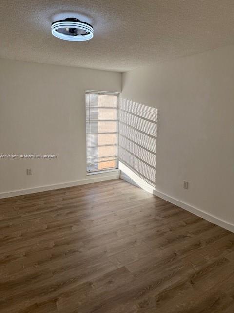 unfurnished room with dark wood-type flooring and a textured ceiling