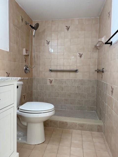 bathroom with a tile shower, vanity, toilet, and tile patterned floors