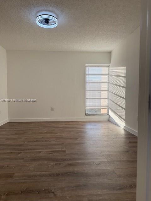 unfurnished room with a textured ceiling and dark hardwood / wood-style floors