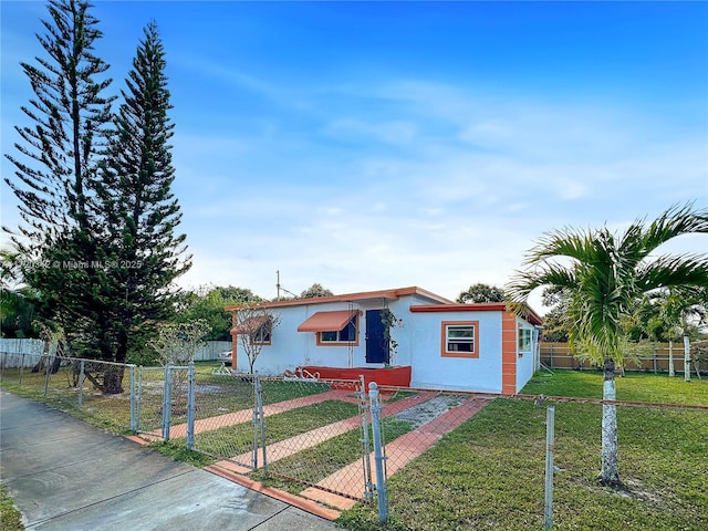 view of front of property with a fenced front yard, a gate, a front lawn, and stucco siding