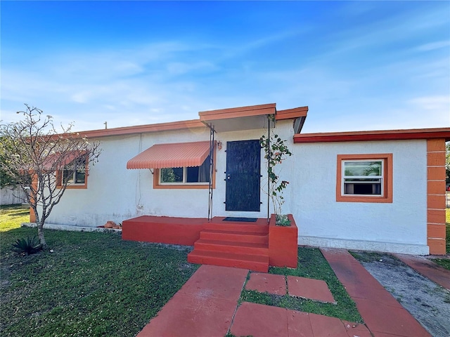 view of front of home featuring entry steps, a front yard, and stucco siding