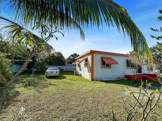 view of side of property with a lawn, fence, and stucco siding