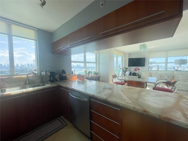 kitchen featuring dark brown cabinetry, sink, light stone counters, stainless steel dishwasher, and light tile patterned floors