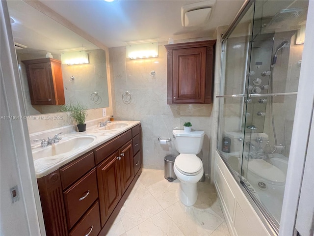 full bathroom featuring shower / bath combination with glass door, vanity, tile walls, and toilet