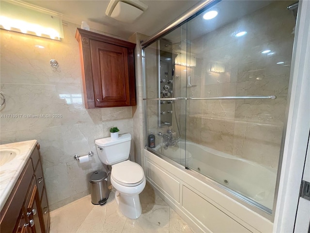 full bathroom featuring vanity, toilet, tile walls, and bath / shower combo with glass door