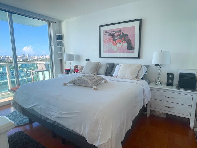 bedroom with multiple windows, expansive windows, and dark hardwood / wood-style floors