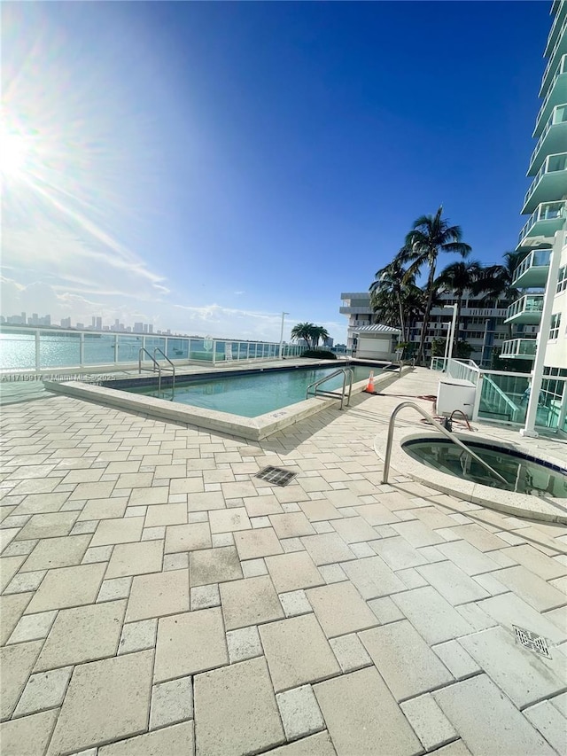 view of swimming pool featuring a patio area and a water view