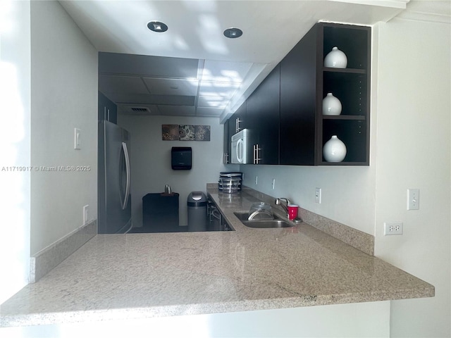 kitchen featuring kitchen peninsula, stainless steel refrigerator, and sink